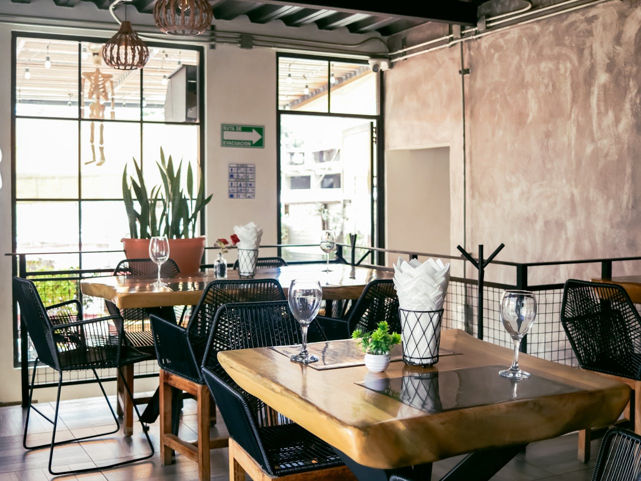 Sunlit modern restaurant interior with wooden tables and chic decor, perfect for a warm dining experience.